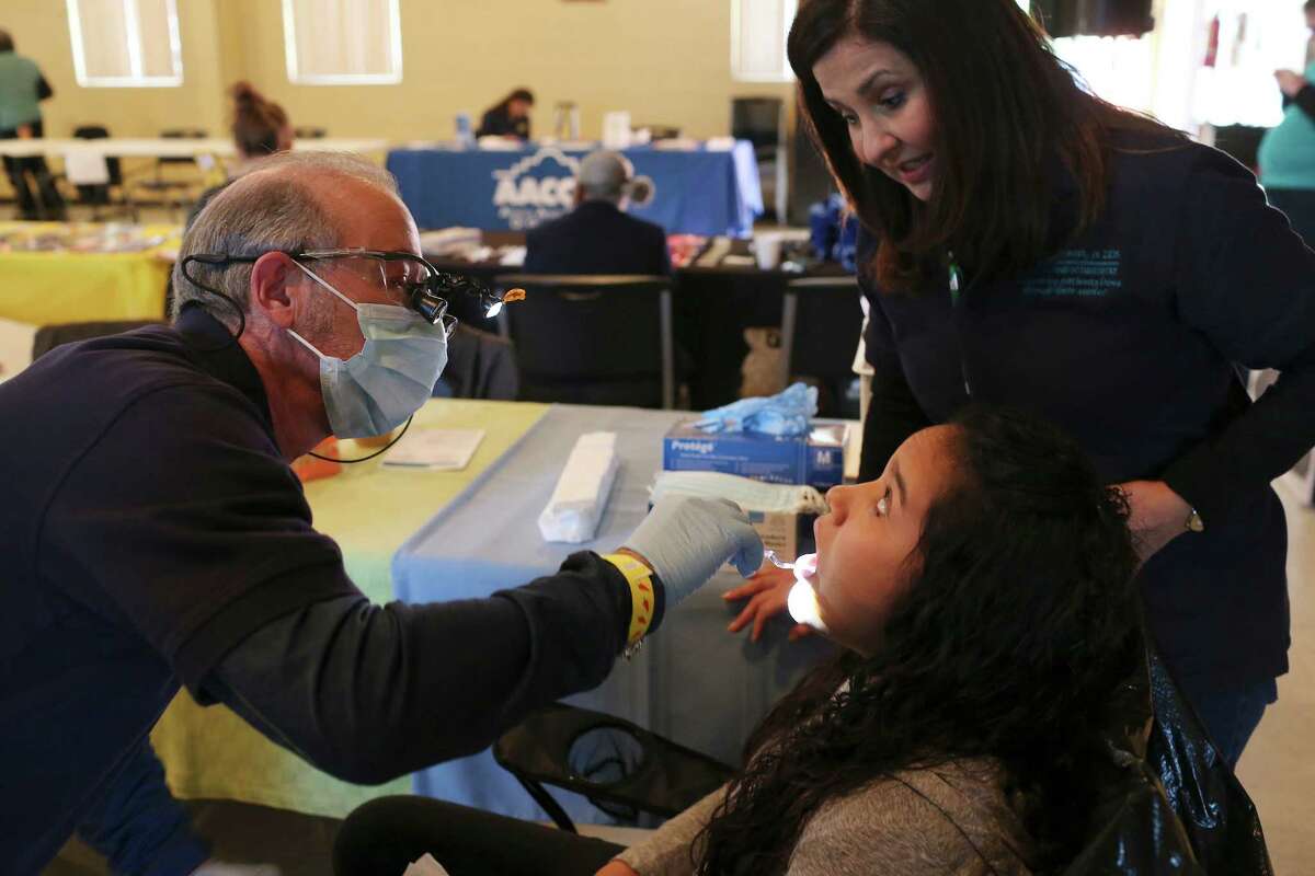 Drs. Billy and Sylvia Stewart perform a dental screening on Dalila Portillo, 17, during the Catholic Charities wellness and community resources fair at Holy Redeemer Catholic Church on Sunday, part of National Nutrition Month.