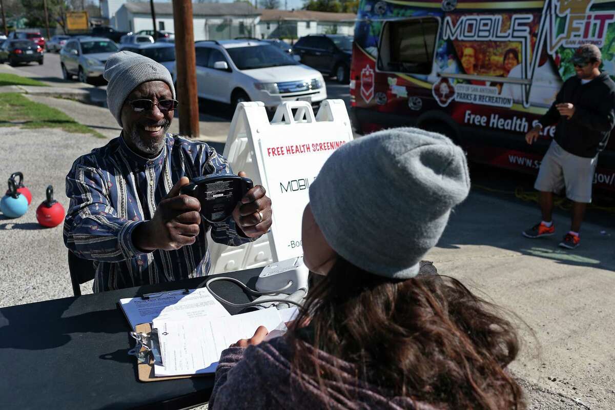 Harold Williams, 64, smiles as he gets his body mass index reading from Tori Martinez at San Antonio Parks and Recreation’s Mobile Fit unit Sunday during the Catholic Charities wellness fair on the East Side.