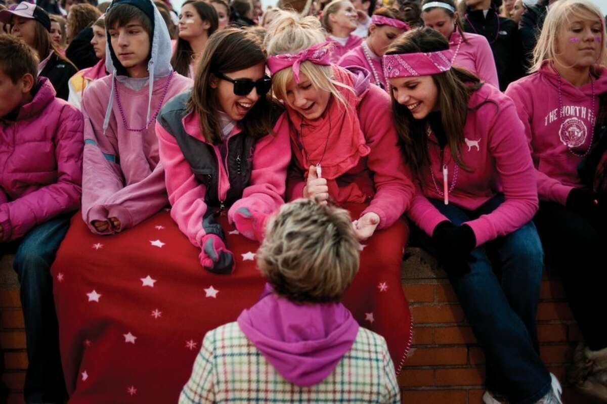 NEIL BLAKE | nblake@mdn.netMidland High School seniors Jordan Stanick, center left, Leah Iseler and Stacy Thurston check out Assistant Principal Kandis Pritchett's pink hair that she sported for the"pink out" at Midland Stadium on Friday.