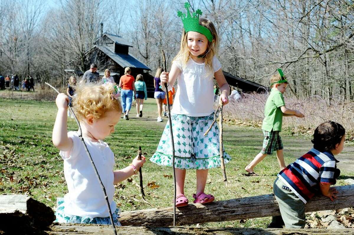 JAKE MAY | for the Daily NewsLily Newton, 2, left, and her sister, Katelynn, 4, both of Midland, play around on a log fence with long walking sticks they found near the Sugarhouse. The girls wore shamrock skirts and a green hat for St. Patrick’s Day on Saturday at the Chippewa Nature Center during Maple Syrup Day, where more than 1,700 people toured the facilities, made crafts and saw demonstrations and other activities.