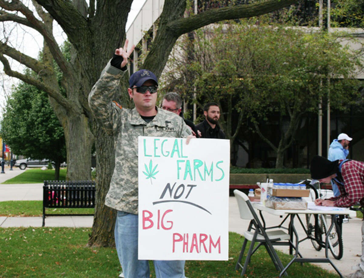 Medical marijuana patient Rhys Williams offers a peace sign to a driver who honked their horn during the rally at Isabella County Courthouse.
