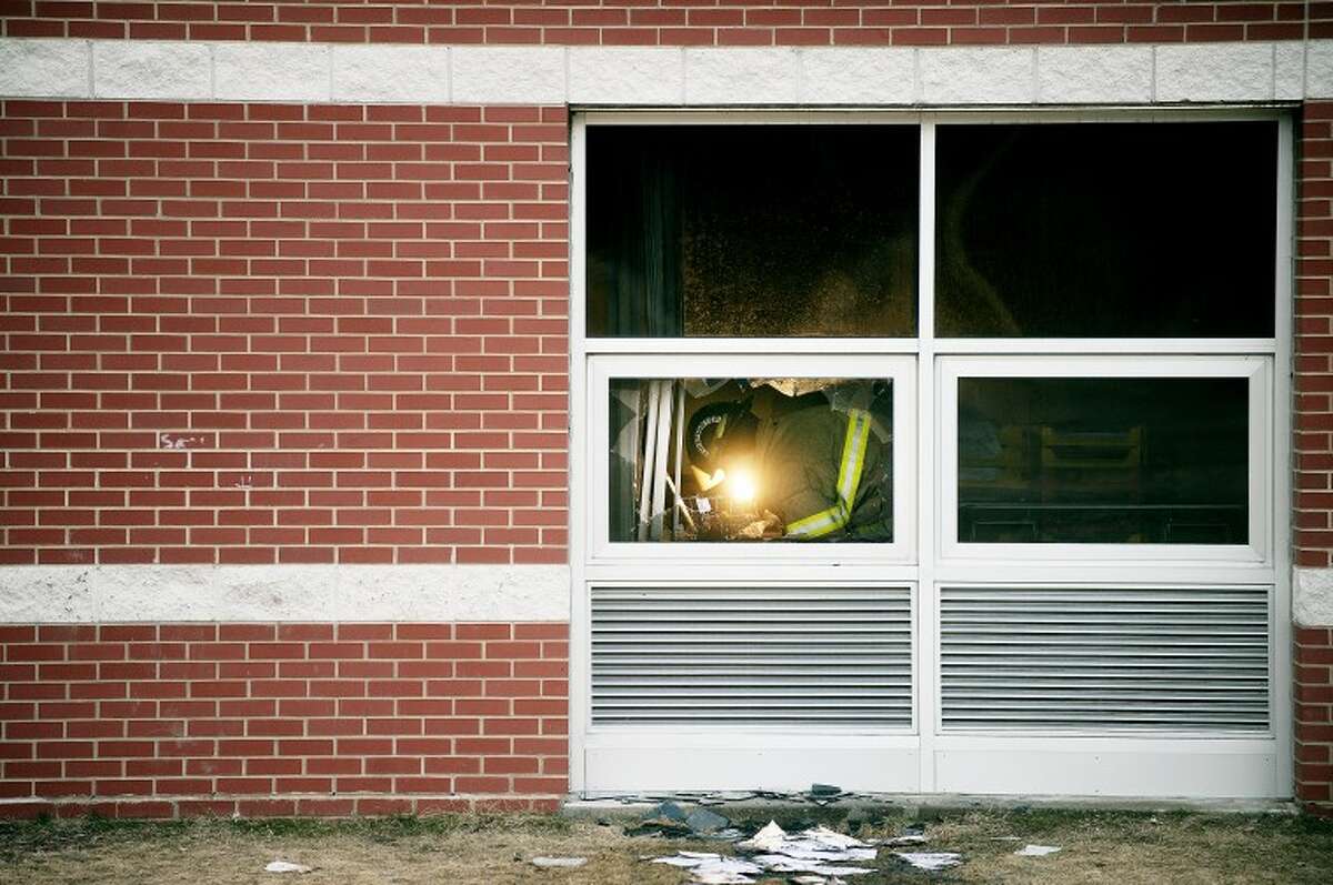 NICK KING | nking@mdn.net A firefighter is seen in the broken window where police believe the suspect broke into the school on Wednesday morning. One classroom was damaged by the fire. School was closed for two days during the investigation and cleanup. A reward is being offered for information.
