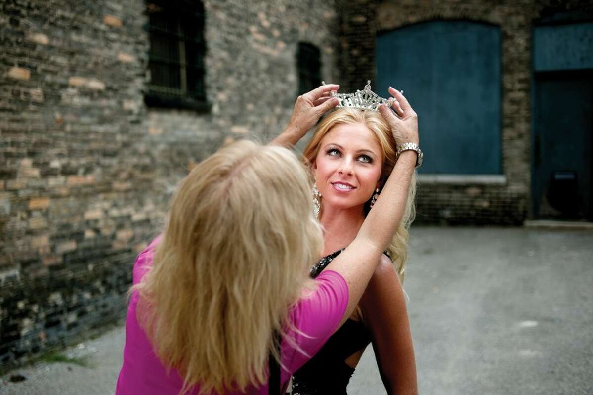 THOMAS SIMONETTI | tsimonetti@mdn.net Miss Bay County Sydney Learman, right, of Linwood has a crown put atop her head by her mother Lindsay Learman in an alley in Downtown Bay City on Friday during a photo shoot. Learman, previously Miss Auburn/Midland, gives up her crown on July 23.