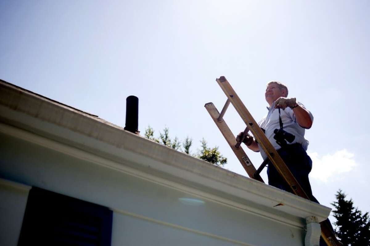 John Spencer of Sherlock Home Inspectors Inc. examines the roof of a Midland home on Thursday. Spencer says he follows a checklist covering structural components of the home, as well as electrical systems, HVAC and plumbing.