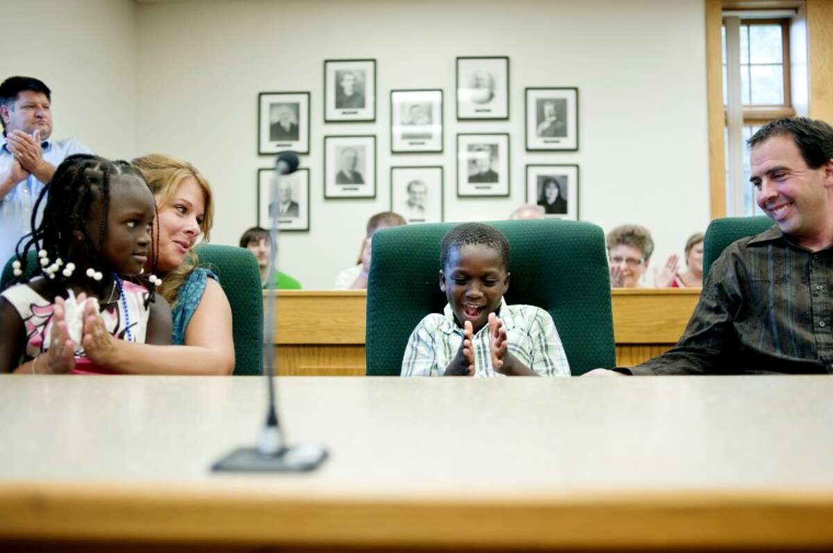 From left, Elmise, Jessica, Armon and Rob Archer celebrate after adoption proceedings in front of Midland County Probate and Family Court Judge Dorene  Allen Wednesday at the Midland County Courthouse. The Archers have been trying to adopt the Haitian children, Elmise and Armon, since 2008. Family and friends crowded the courtroom to watch the children legally become a part of the Archer family.