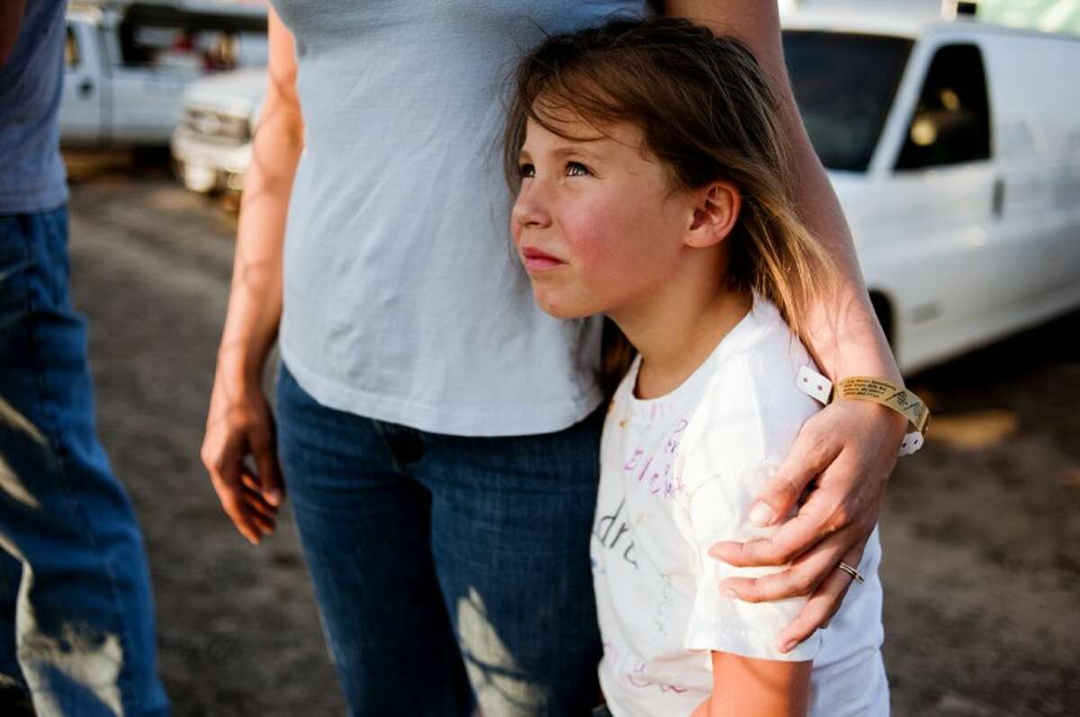 Kendra Walch, 6, of Remus, cuddles up close to her mother, Tia Walch, while watching fireworks explode at Tri-City Motor Speedway on Friday at the grand opening. Kendra's father, Terry, raced a mini-sprint car.