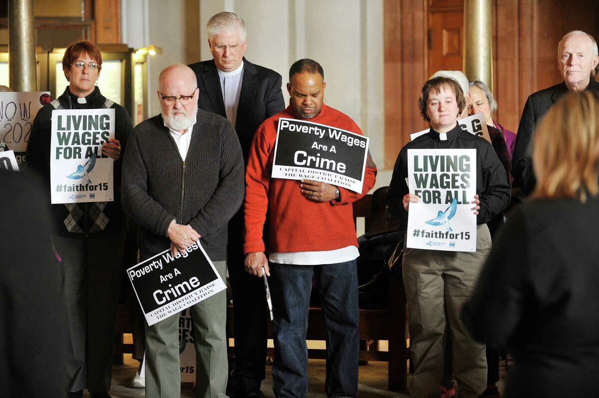 People pray as a coalition of faith groups held a rally calling on legislators to pass an increase in the minimum wage to $15 at the Capitol on Monday, March 21, 2016 in Albany, N.Y. (Paul Buckowski / Times Union)