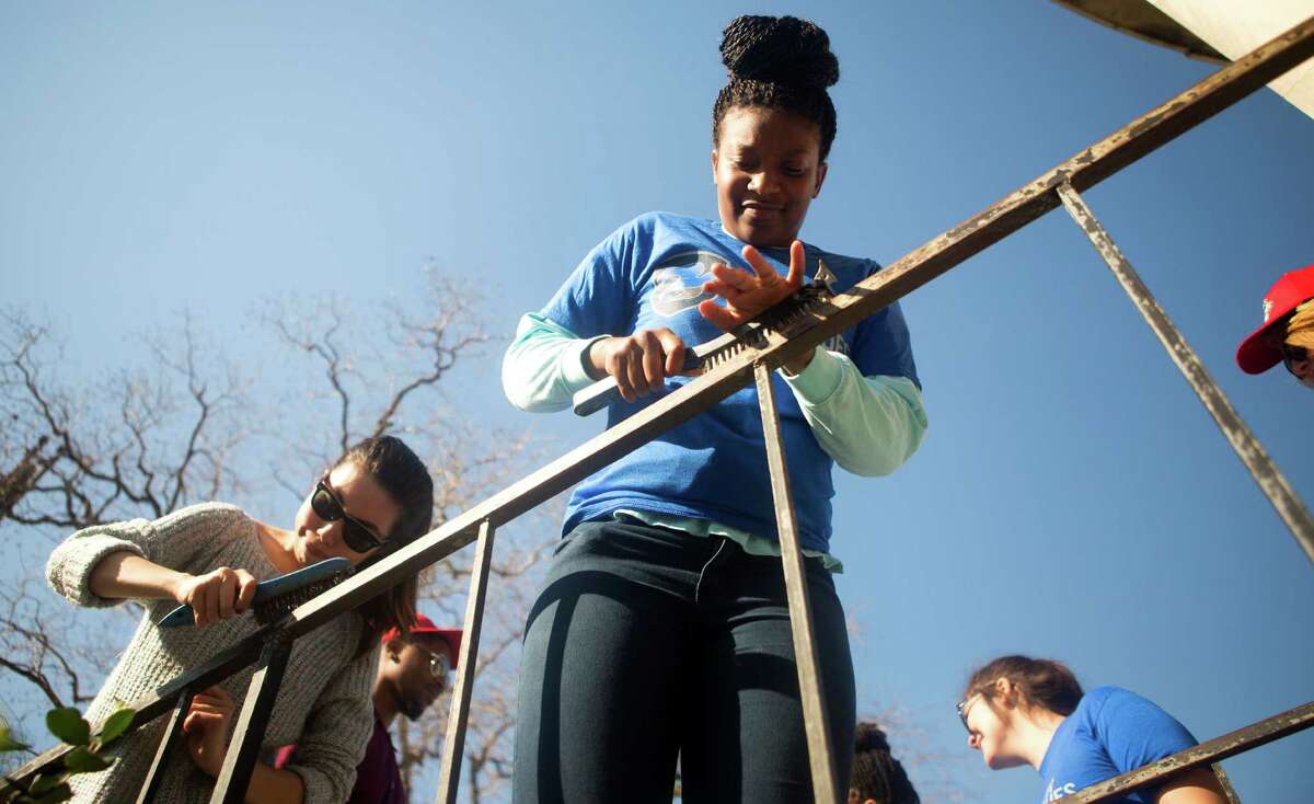 Deneesha Jones, right, uses a wire brush on a rail as she, and other volunteers work on the Blue Triangle Community Center during Martin Luther King Jr. Day of Service in Houston. The 2016 NCAA Men's Final Four Local Organizing Committee collaborated with Mission Continues, to organize 300 volunteers as they cleaned, organized and beautified the community center in the Third Ward.. (Cody Duty / Houston Chronicle)