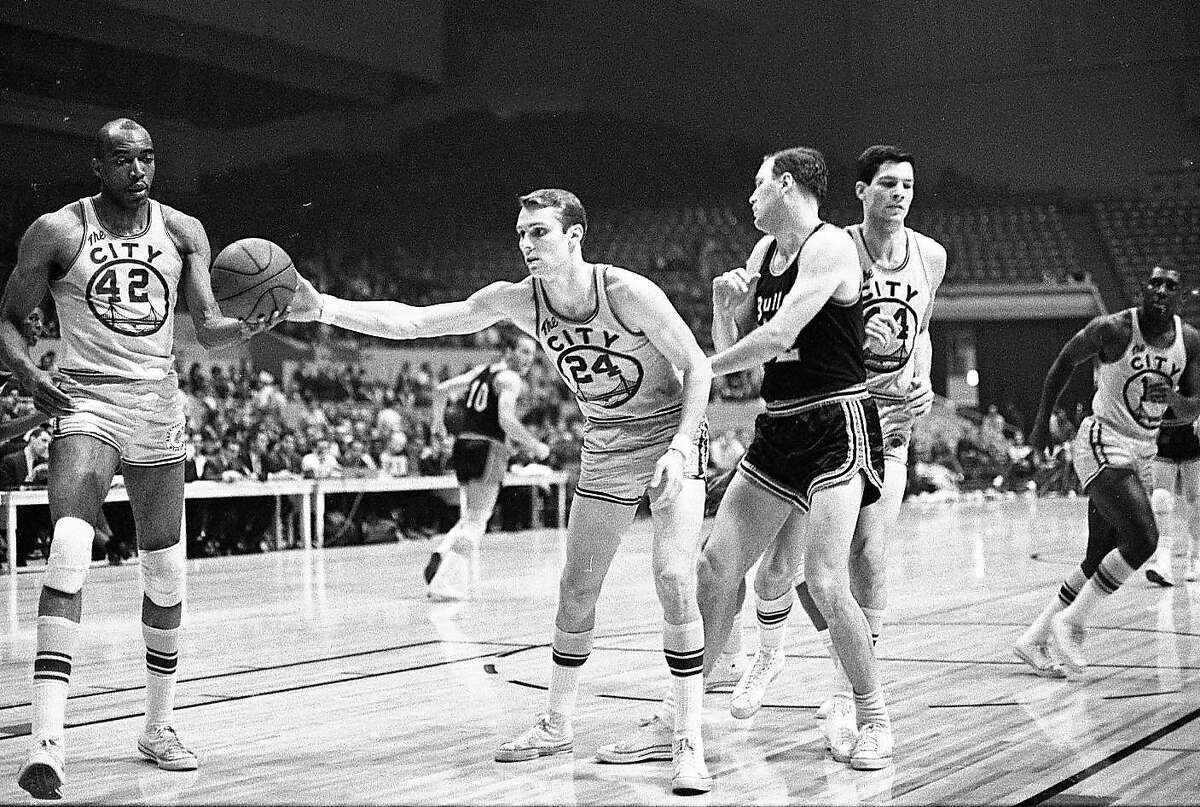 Wearing his distinctive “The City” jersey, Warrior Rick Barry hands the ball to Nate Thurmond during a game against the Baltimore Bullets at the Cow Palace in January 1967.