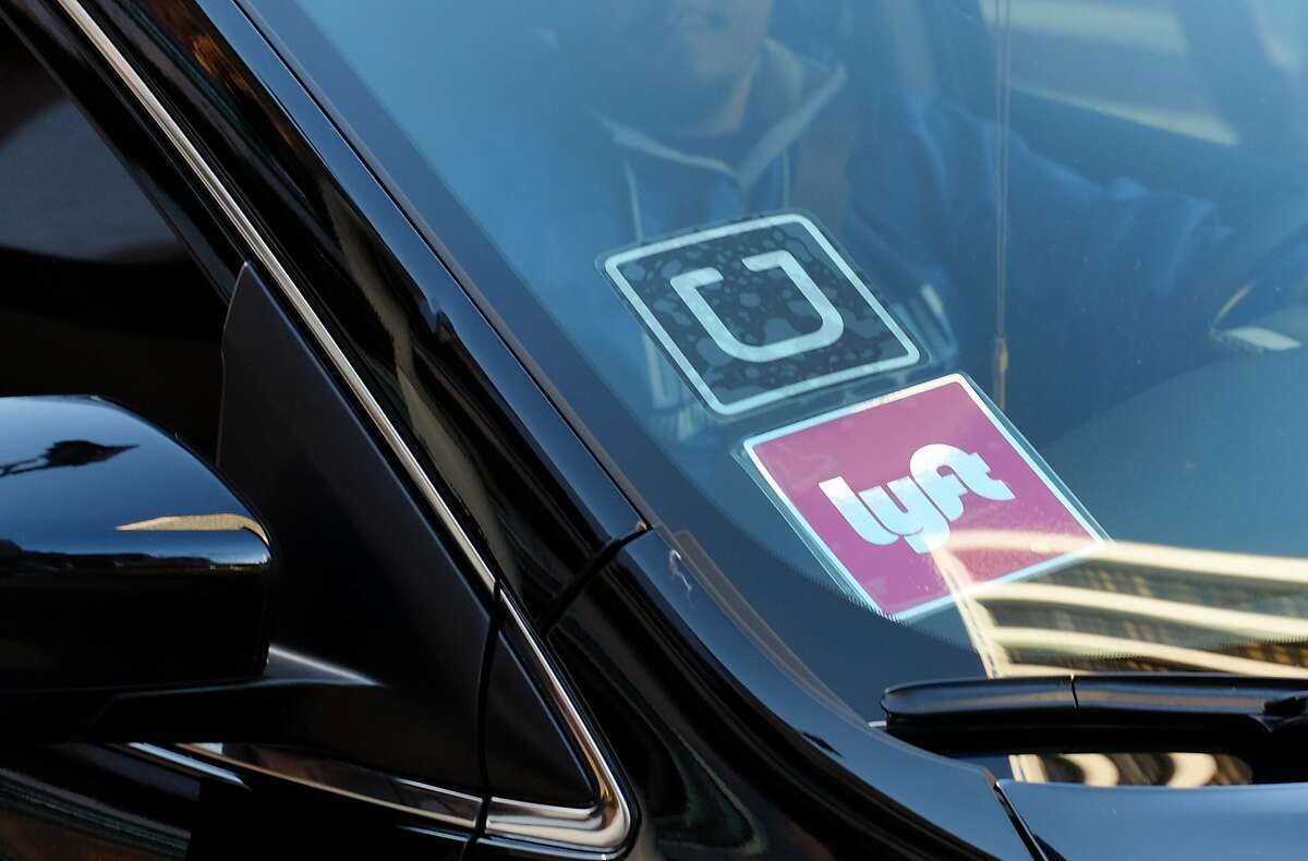 In this Tuesday, Jan. 12, 2016 file photo, a driver displaying Lyft and Uber stickers on his front windshield drops off a passenger in downtown Los Angeles, Calif. Passengers arriving at Los Angeles International Airport will be allowed to leave in an UberX car starting Thursday, Jan. 21. (AP Photo/Richard Vogel, File)