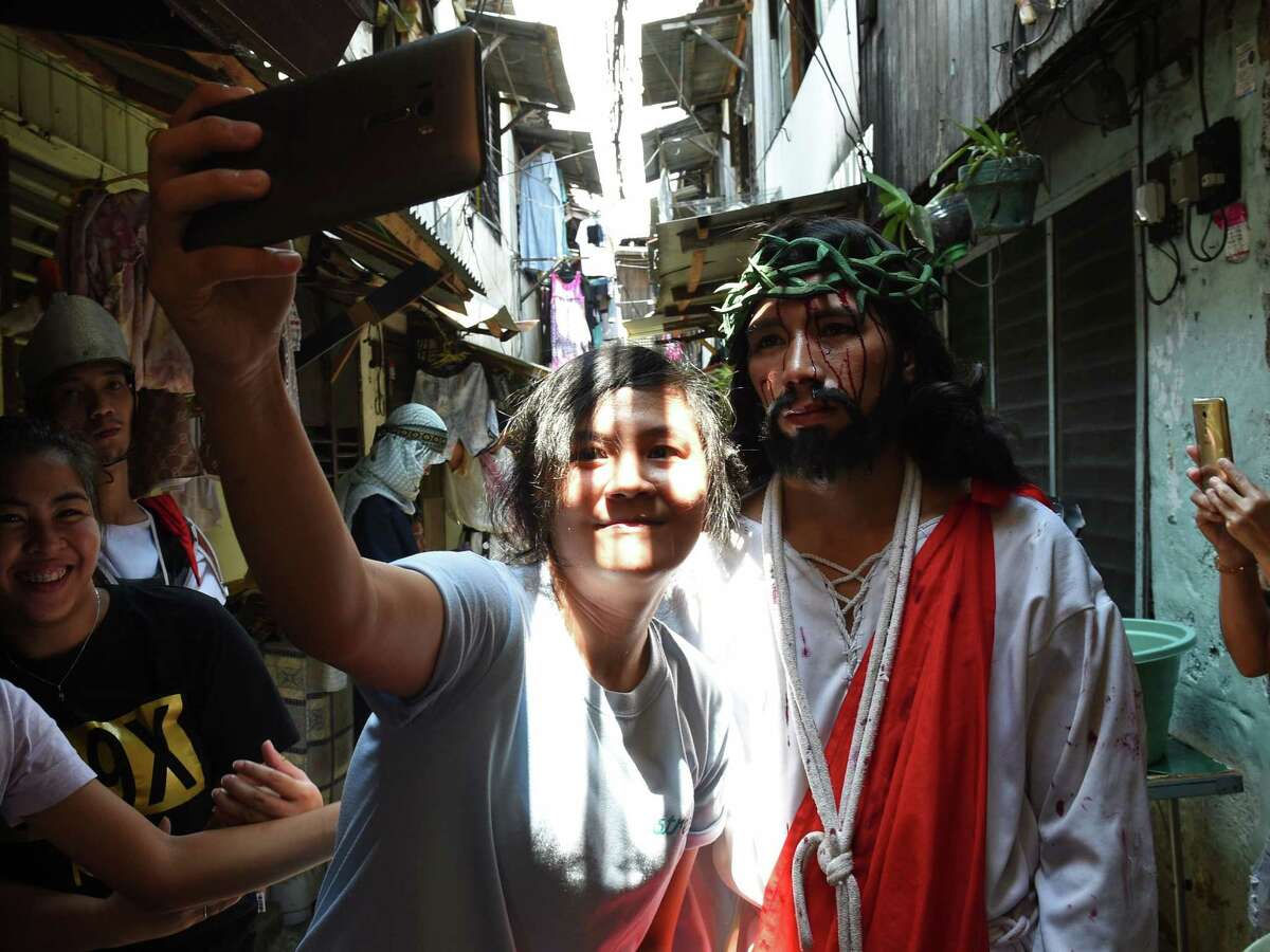 A spectator takes a selfie with an actor playing the role of Jesus during the reenactment of the suffering and crucifixion of Jesus in a street play as part of Lenten observance during Holy Week in Manila on March 24, 2016, ahead of Easter. Christian believers around the world mark the Holy Week of Easter in celebration of the crucifixion and resurrection of Jesus Christ. / AFP / TED ALJIBE
