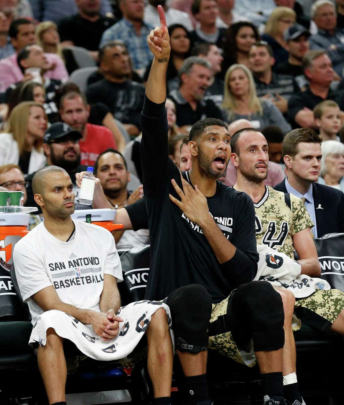Spurs’ Tim Duncan (center) roots for the guys on the floor while seated with teammate Tony Parker (left) and Manu Ginobili (right) during the game against the Miami Heat at the AT&T Center on March 23, 2016.