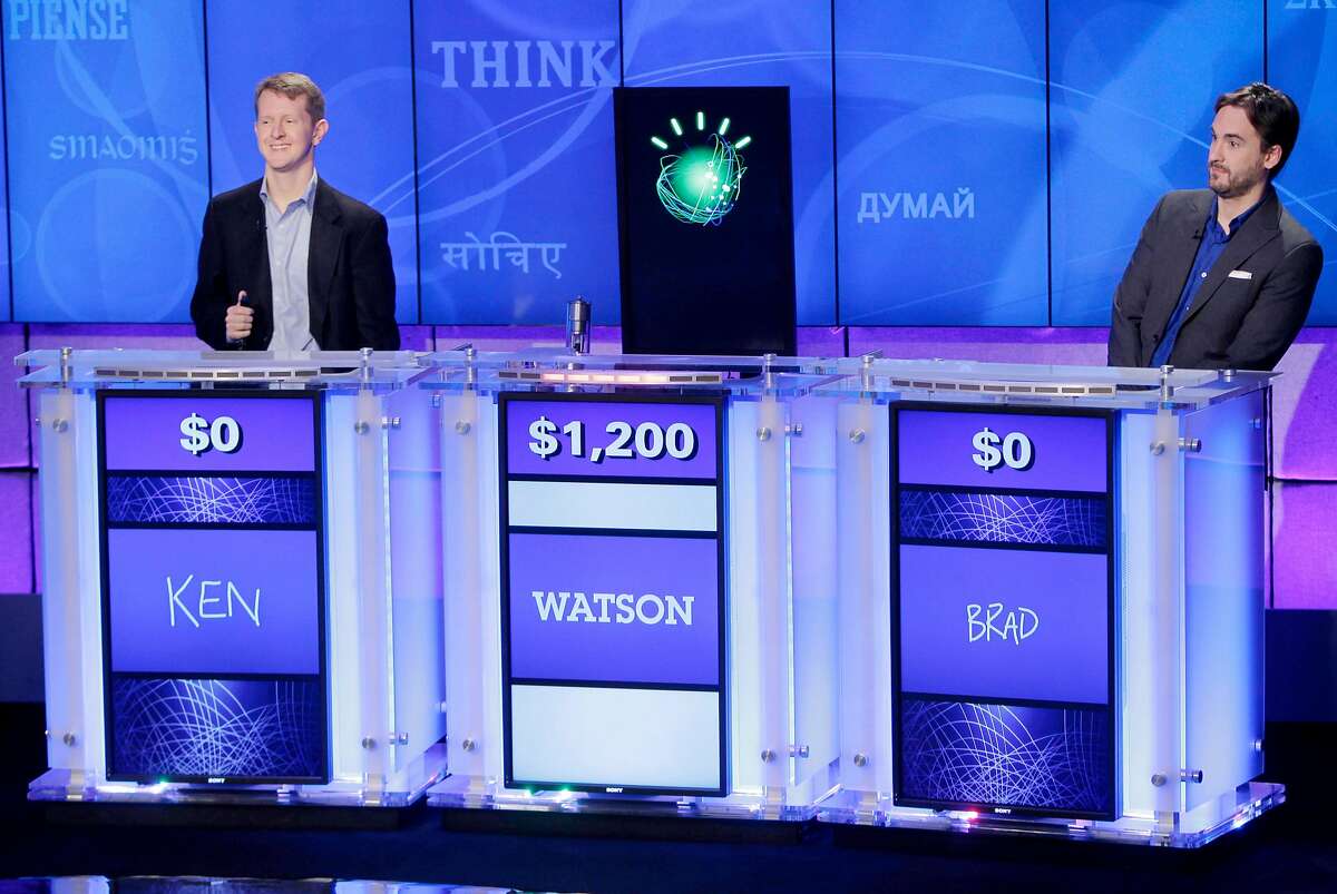FILE - In this file photo of Jan. 13, 2011, "Jeopardy!" champions Ken Jennings, left, and Brad Rutter, right, look on as the IBM computer called "Watson" beats them to the buzzer to answer a question during a practice round of the "Jeopardy!" quiz show in Yorktown Heights, N.Y. IBM announced Thursday, Jan. 9, 2014 that it's investing over $1 billion to give its Watson cloud computing system its own business division and a new home in the heart of New York City (AP Photo/Seth Wenig, File)