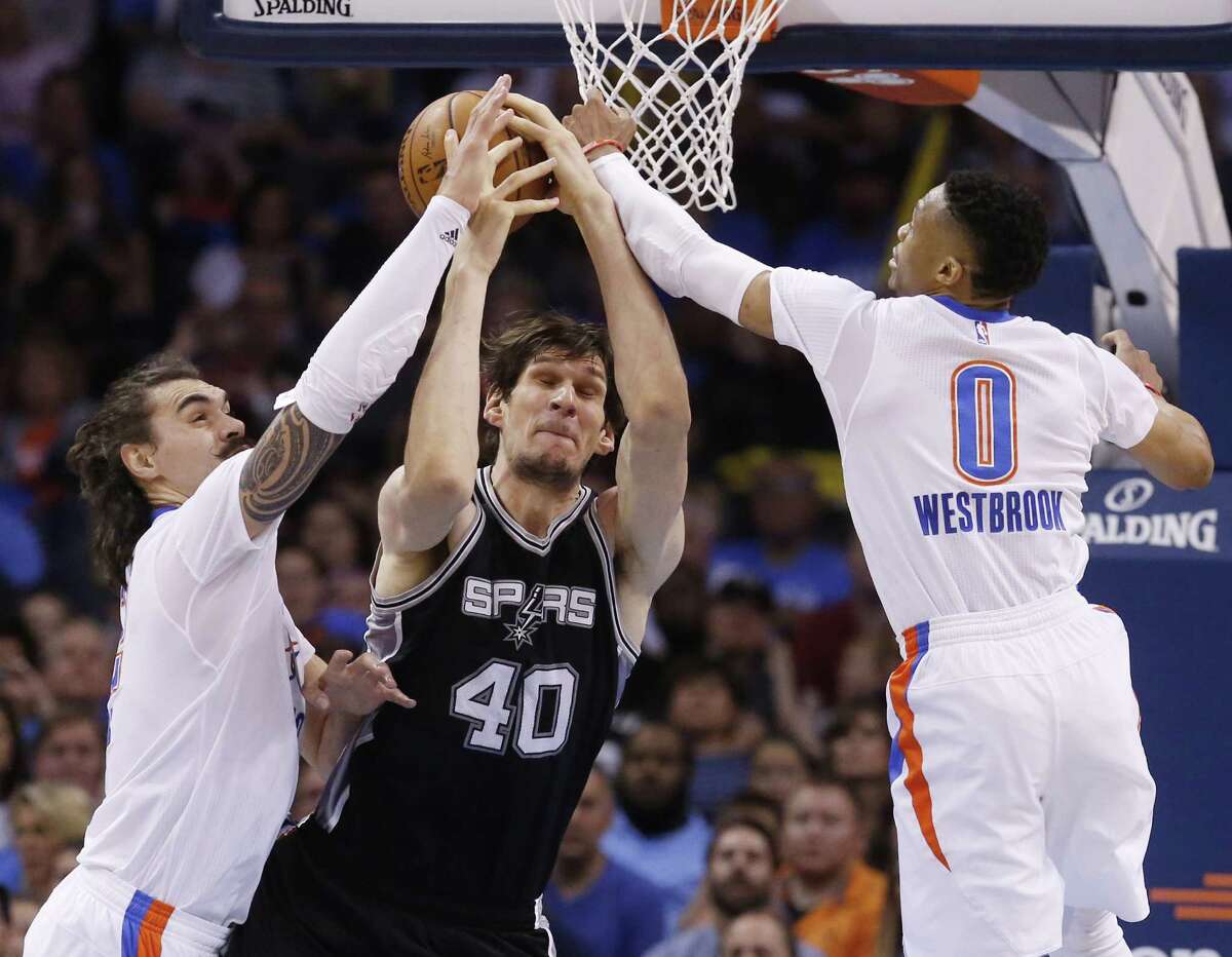 Oklahoma City Thunder center Steven Adams, left, San Antonio Spurs center Boban Marjanovic (40) and guard Russell Westbrook (0) reach for a rebound in the third quarter of an NBA basketball game in Oklahoma City, Saturday, March 26, 2016. Oklahoma City won 111-92. (AP Photo/Sue Ogrocki)