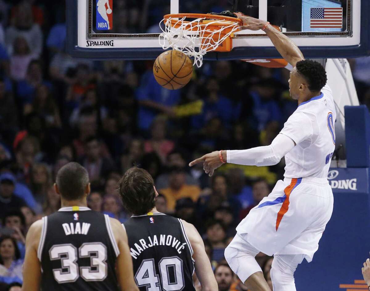 Thunder guard Russell Westbrook dunks in front of San Antonio Spurs center Boris Diaw (33) and center Boban Marjanovic (40) in the third quarter in Oklahoma City on March 26, 2016.