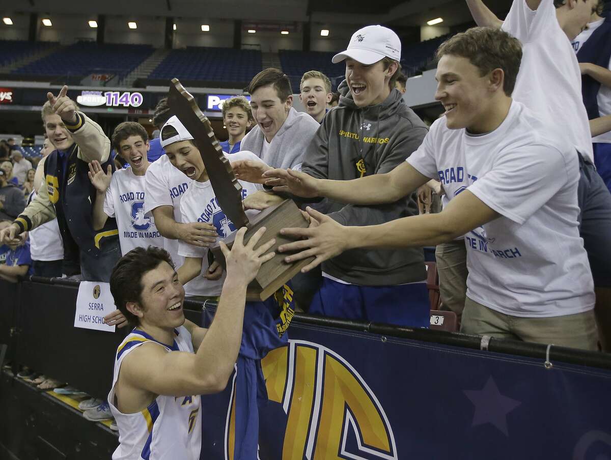 Junipero Serra's Cole Galli, left, carries the championship trophy past supporters after Junipero Serra defeated Long Beach Poly 48-43 in the CIF boys' Division II high school basketball championship game Saturday, March 26, 2016, in Sacramento, Calif. (AP Photo/Rich Pedroncelli)