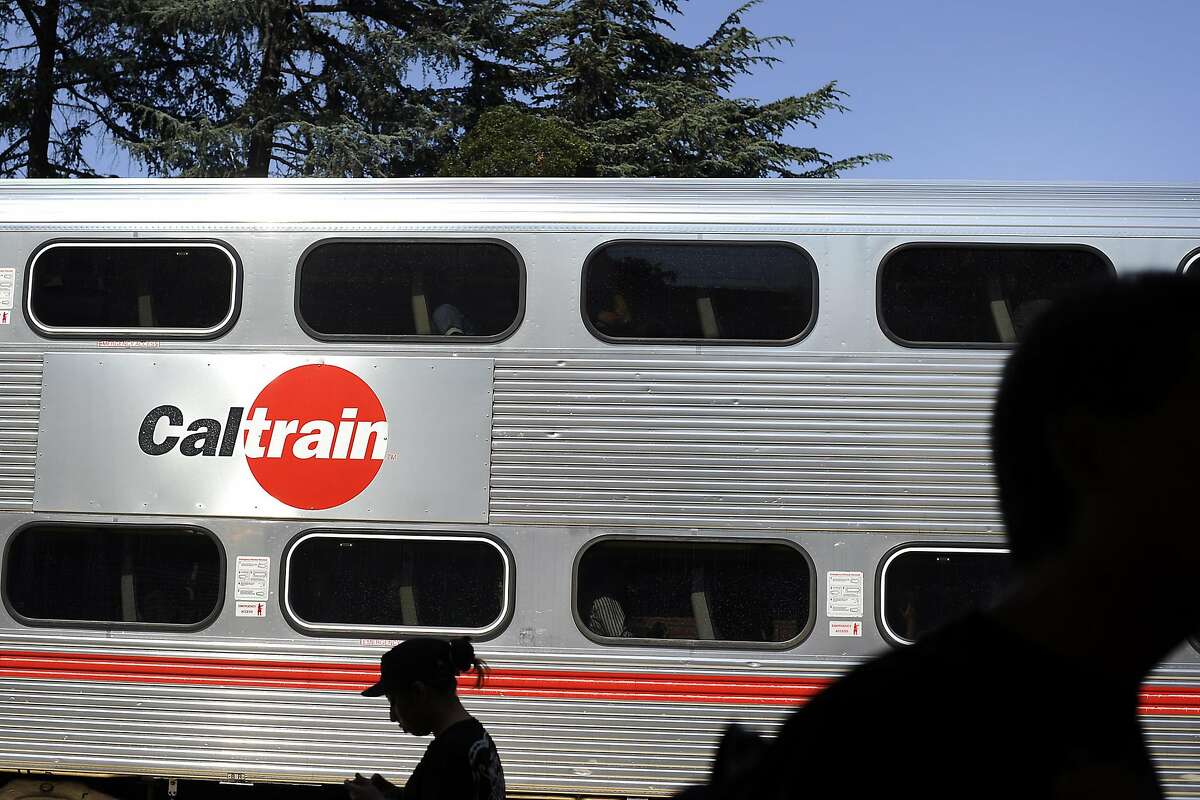In this file photo, people wait on the platform as a Caltrain pulls into the University Ave. stop in Palo Alto.