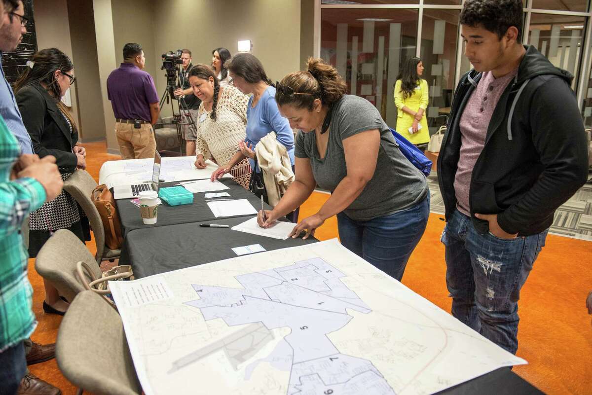 Sandra Estrada, center, and her son Ethan Estrada, right, a sophomore at South San High School, sign into a community meeting for parents, community leaders and other members of the South San Antonio Independent School District at Palto Alto College in San Antonio, Texas on Tuesday, March 29, 2016.
