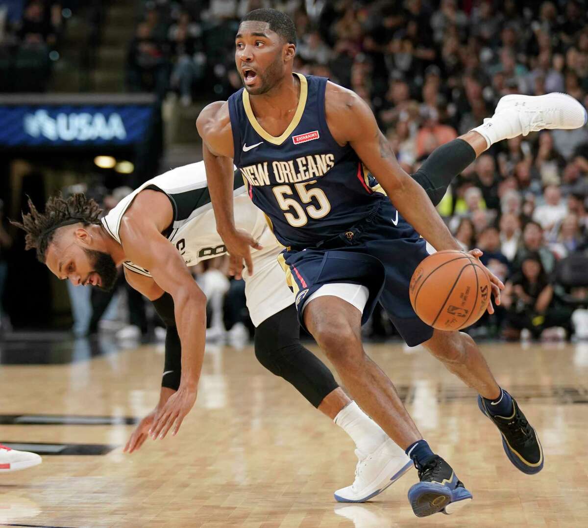 New Orleans Pelicans' E'Twaun Moore (55) drives past San Antonio Spurs' Patty Mills during the first half of an NBA basketball game, Thursday, March 15, 2018, in San Antonio. (AP Photo/Darren Abate)
