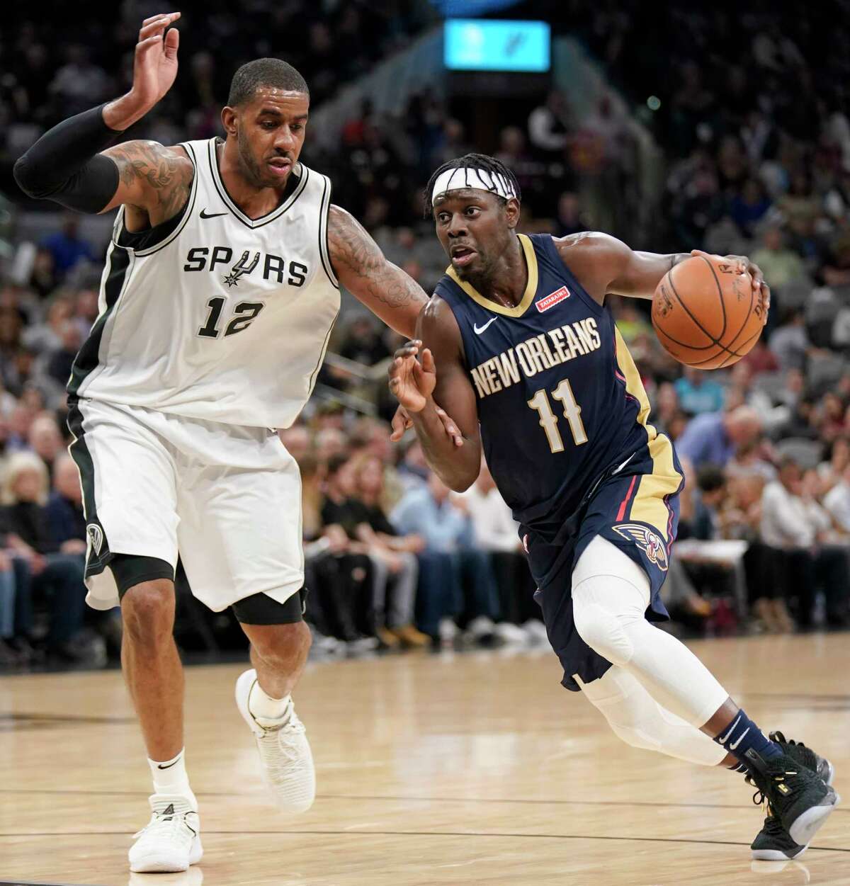 New Orleans Pelicans' Jrue Holiday (11) drives past San Antonio Spurs' LaMarcus Aldridge during the first half of an NBA basketball game, Thursday, March 15, 2018, in San Antonio. (AP Photo/Darren Abate)