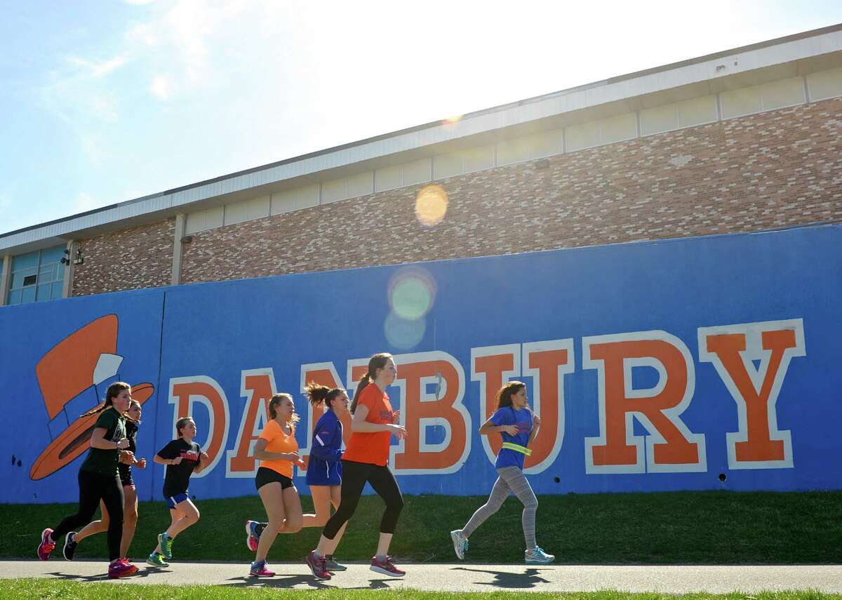 Members of the Danbury High School girls track team run behind the school during practice on Wednesday afternoon. 