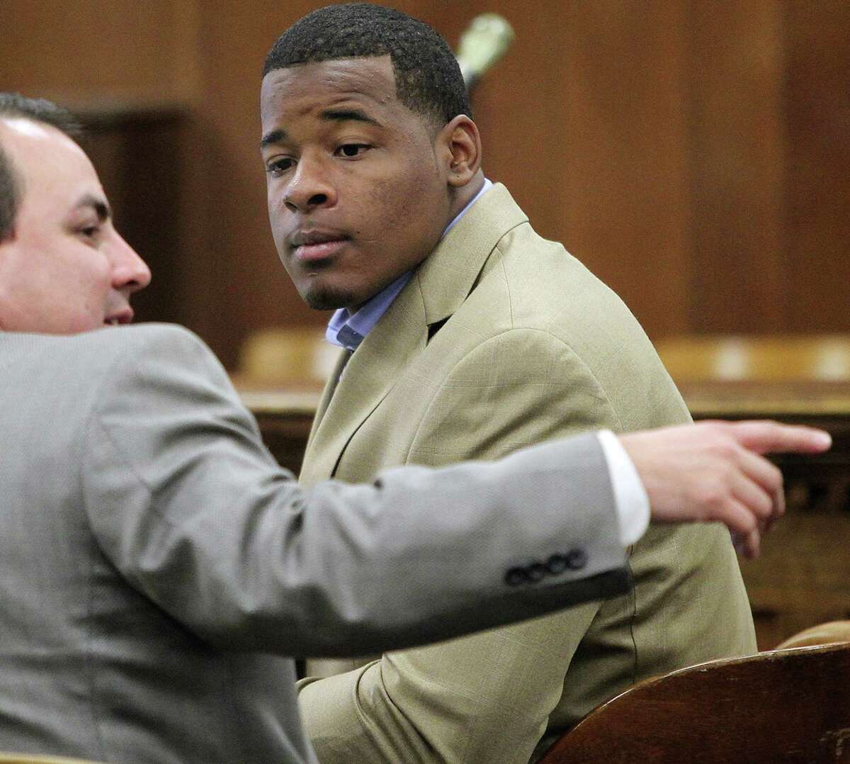 FILE - In this Jan. 23, 2014, file photo, former Baylor football player Tevin Elliott waits with a unidentified lawyer in a McLennan county courtroom in Waco, Texas. A woman has filed a federal lawsuit against Baylor University contending that the largest Baptist school in the country was "deliberately indifferent" to sexual assault allegations against a former football player. The lawsuit alleges that Baylor failed to act against Tevin Elliott despite receiving six complaints from women claiming he assaulted them.