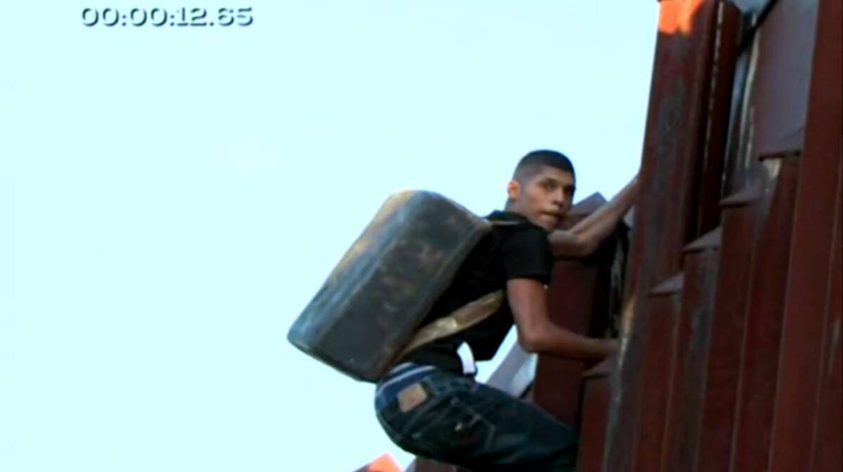 Video footage shot by Carolina Rocha, a journalist for Azteca Noticias in Mexico City, on March 16 shows two apparent drug smugglers carrying backpacks while scaling a steel fence along the U.S.-Mexico border in Nogales, Ariz., crouching while running along the fence and apparently talking on a phone.
