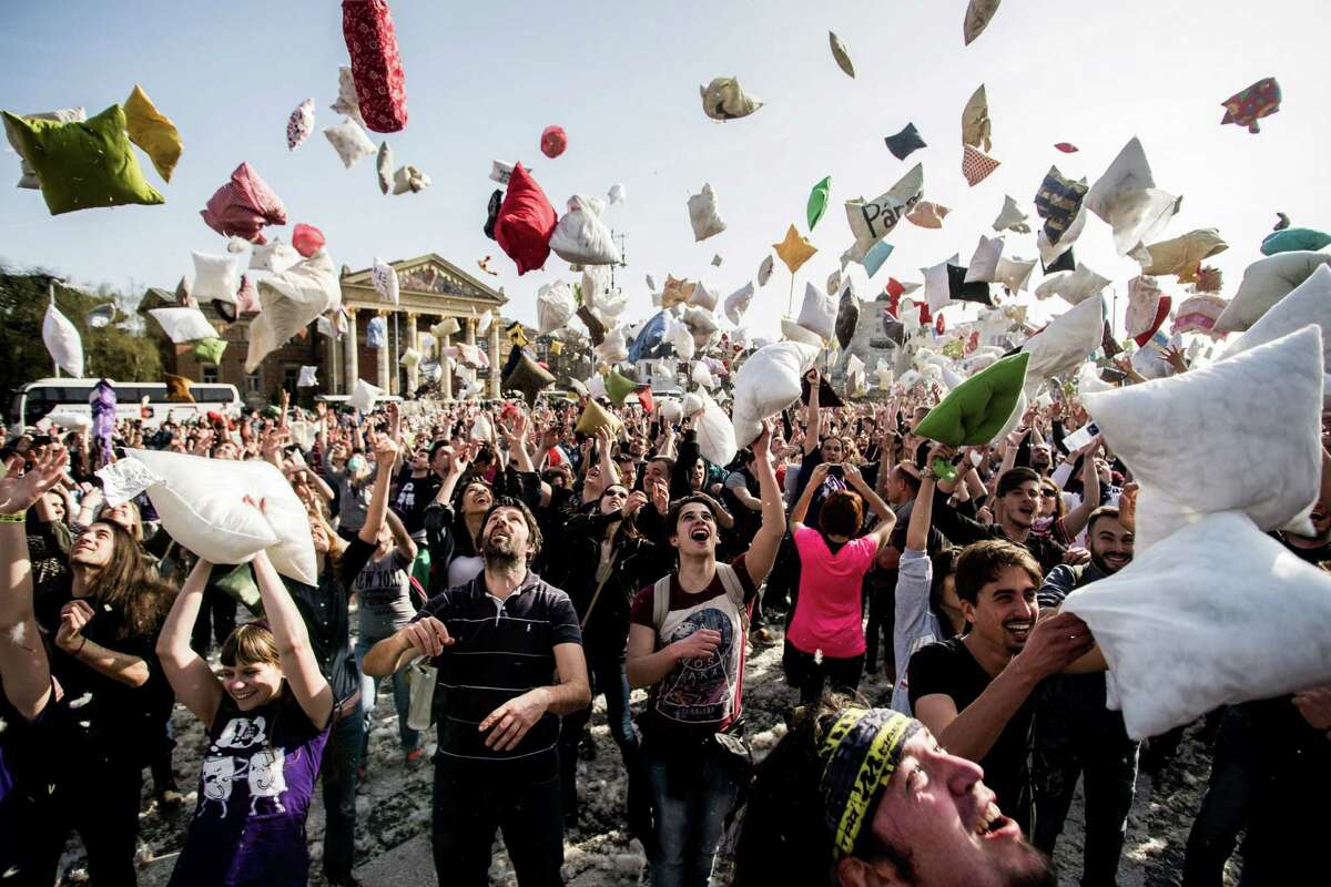 Young people throw pillows into the air as they mark International Pillow Fight Day in the Heroes' Square, in central Budapest, Hungary, Saturday, April 2, 2016. (Zoltan Balogh/MTI via AP)