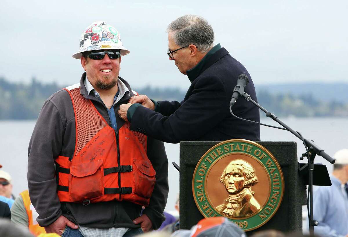 Governor Jay Inslee pins a Washingtonian-of-the-Day apple pin on electrician Jason Hops during a ribbon-cutting ceremony for the new State Route 520 floating bridge.  Inslee is courting organized labor in his bid for reelection.