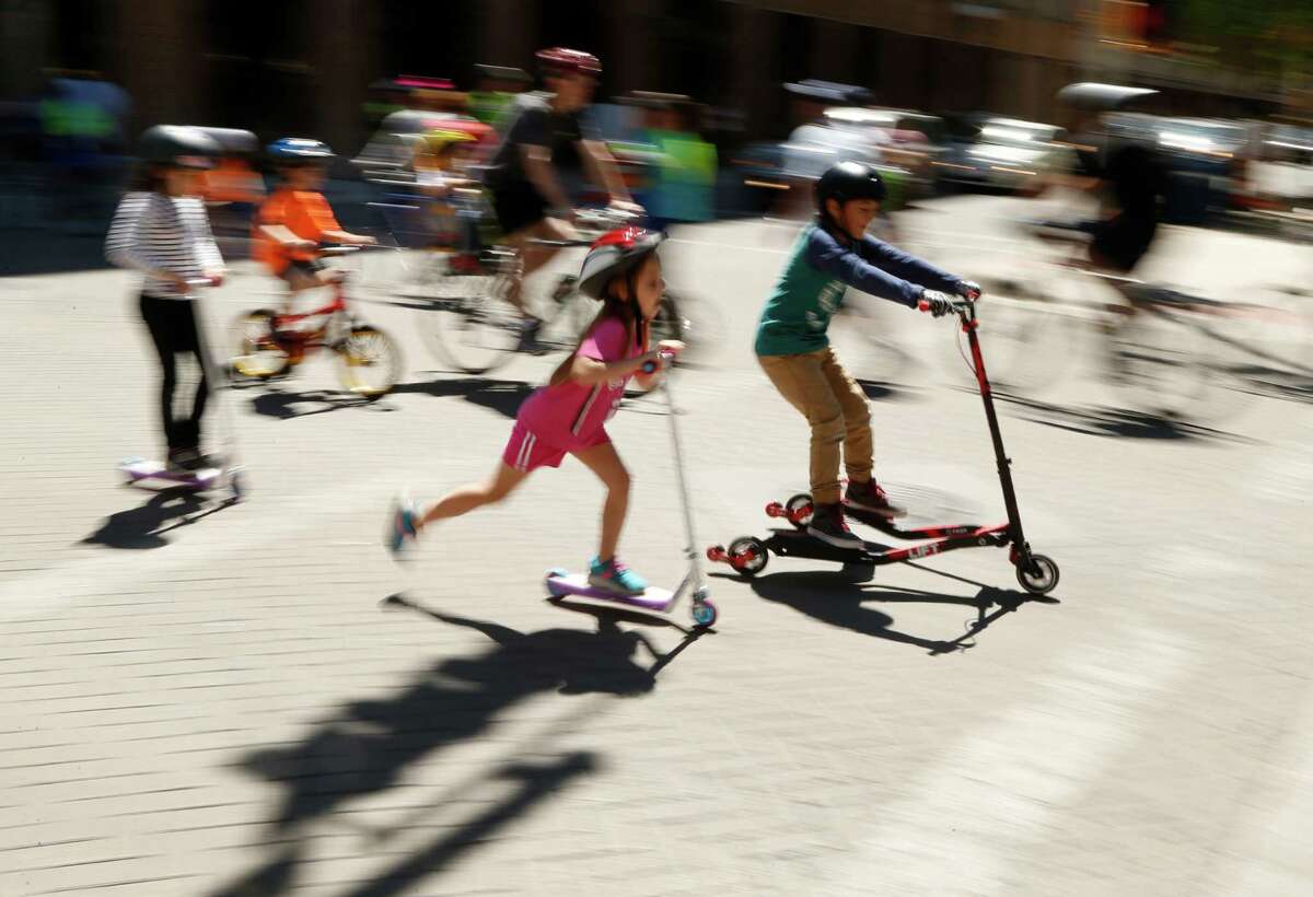 Kids on skateboard join others during the 10th s?’colov?’a in downtown San Antonio. This free event turns city streets into a safe place for people to exercise and play when they become car-free from 11 a.m. to 3 p.m on Sunday,April 3, 2016. Slow shitter speed with pan gives the photo the effect it has.