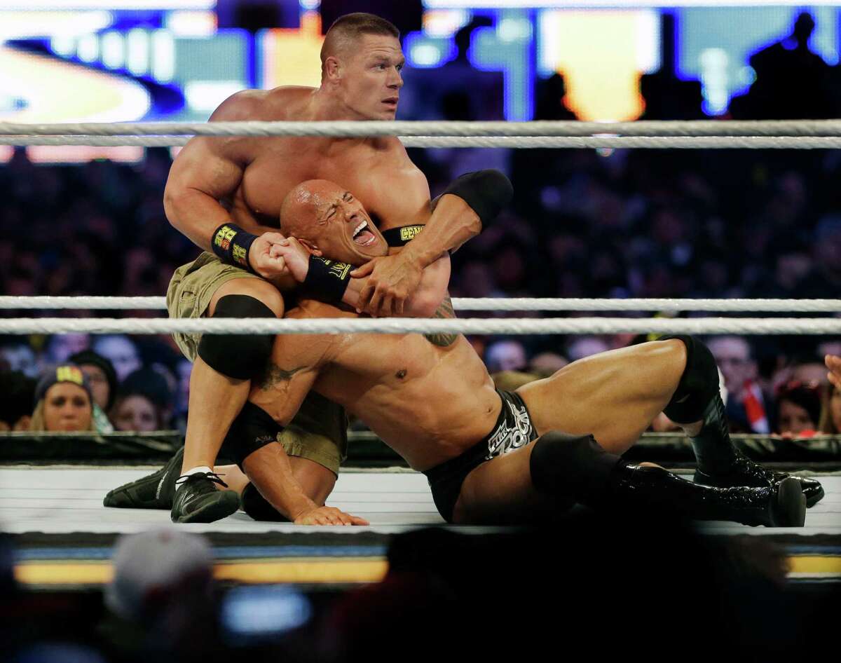 Wrestler John Cena, top, chokes The Rock as they face off during Wrestlemania in East Rutherford, N.J.