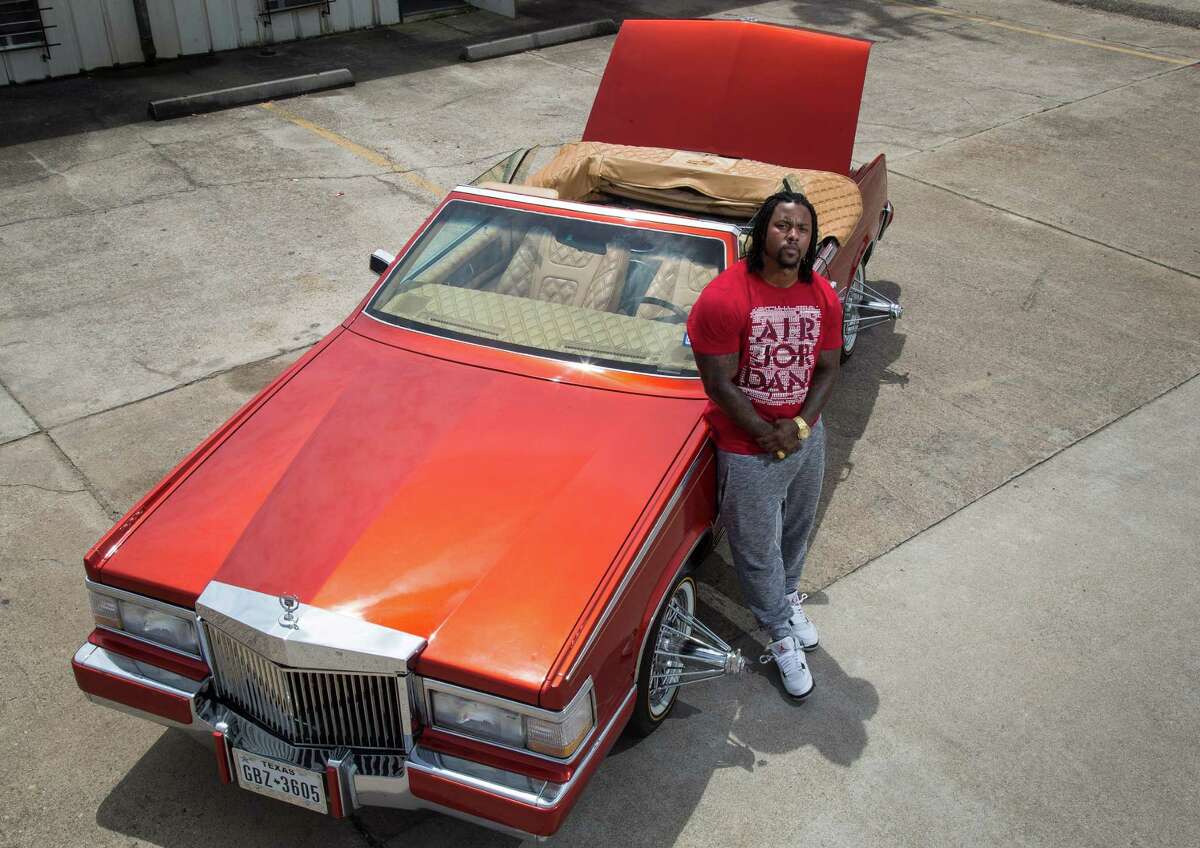 Chris Lockett poses for a portrait with his custom Cadillac Eldorado in Houston. Lockett has worked on the car for three years, and he will drive it in this year's Houston Art Car Parade.