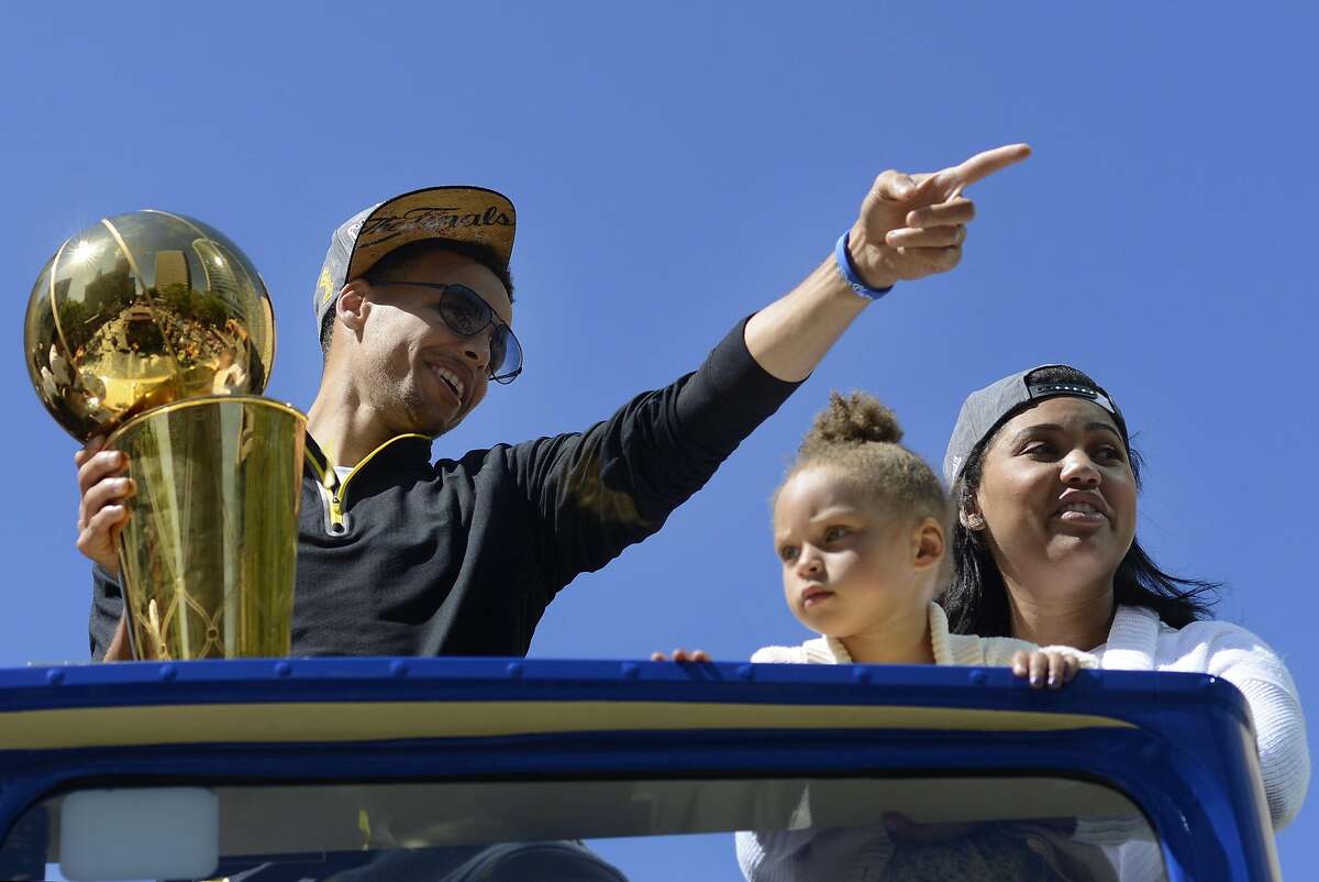 Stephan Curry, Ayesha Curry, and their daughter Riley Curry ride down Broadway Street for the parade celebrating the Golden State Warriors' first NBA Final win in 40 years.