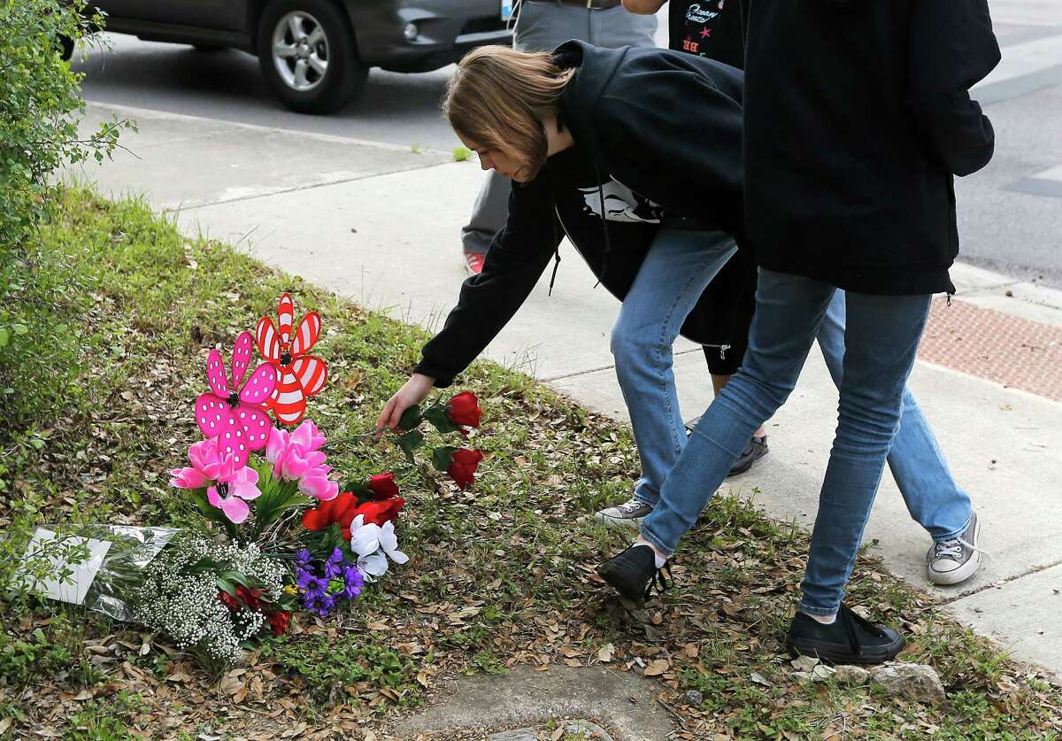 A girl places flowers at a memorial for Mailani Godin near Mount Tipton Street and West Avenue. The 12-year-old was struck by a car there as she attempted to cross West Avenue.