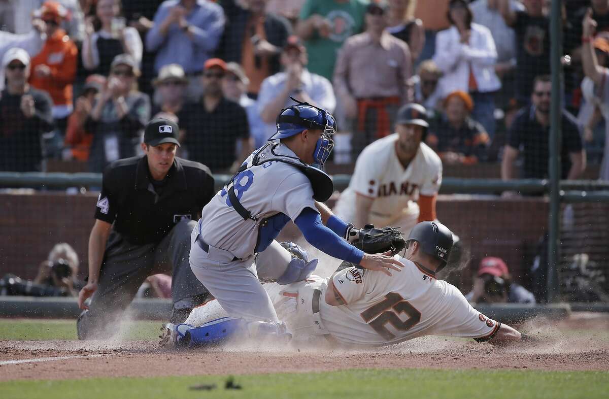Giants' Joe Panik, 12 beats the tag by Dodgers' catcher Austin Barnes, 28 on a Buster Posey, 28 double in the sixth inning to give the Giants a 7-4 lead, as the San Francisco Giants take on the Los Angeles Dodgers during their home opener of the 2016 MLB season, at AT&T Park in San Francisco, California on Thurs. April 7, 2016.