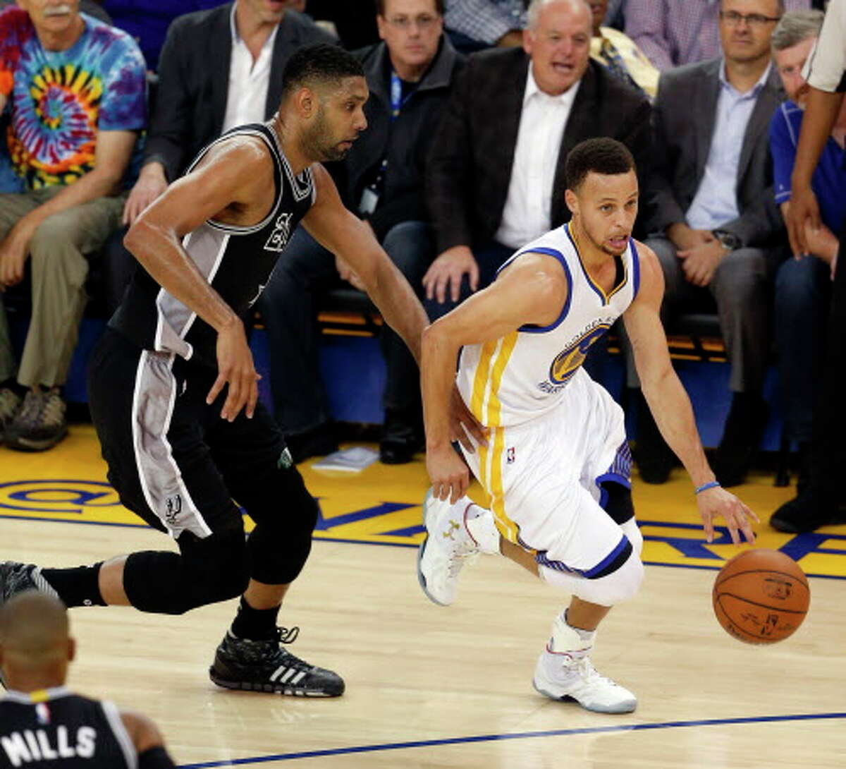Golden State Warriors' Stephen Curry dribbles past San Antonio Spurs' Tim Duncan in 1st quarter during NBA game at Oracle Arena in Oakland, Calif., on Thursday, April 7, 2016.
