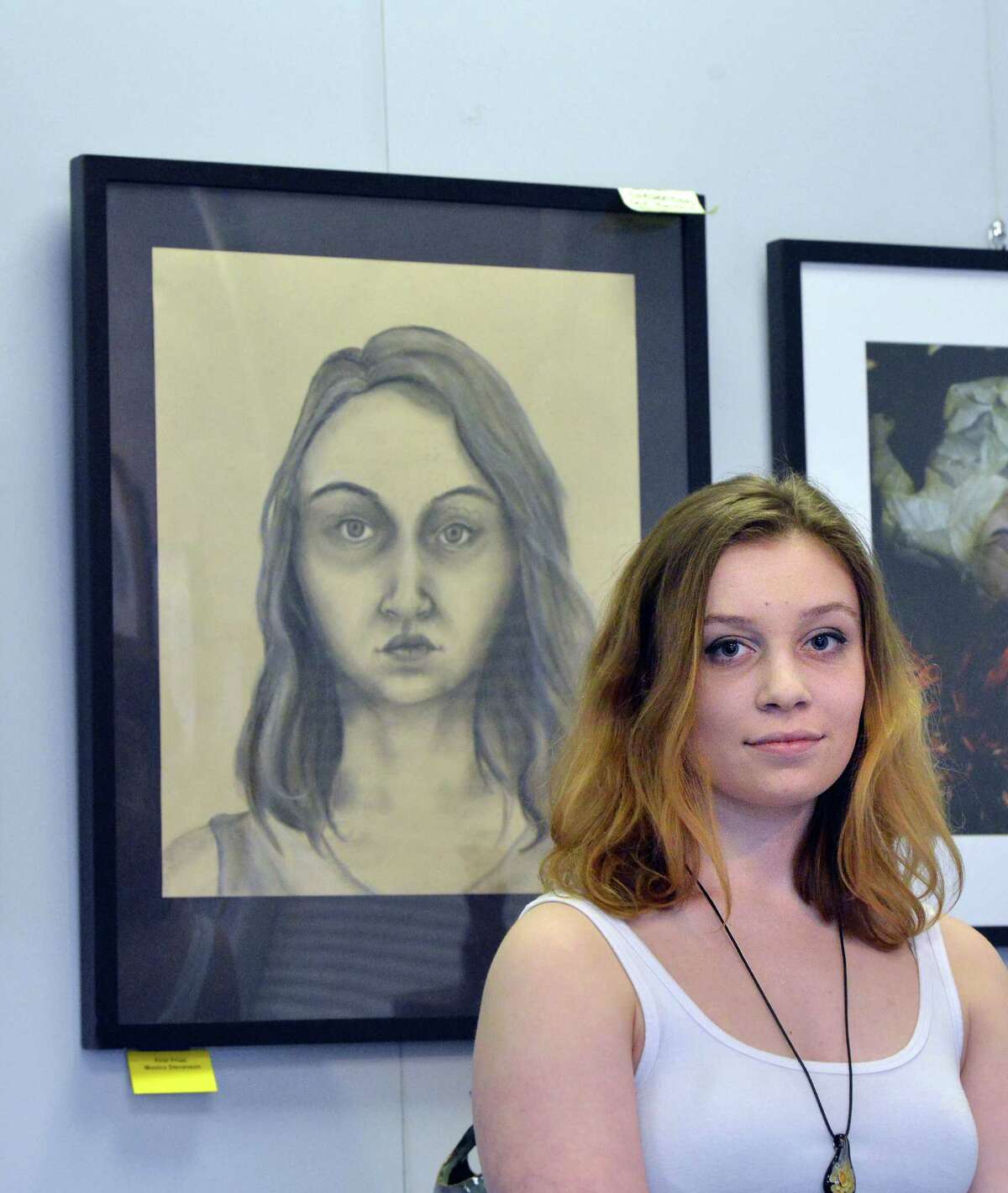 Greenwich High School senior Monica Stevenson,18, with her self-portrait done in charcoal that was part of the Art Society of Old Greenwich Spring Art Show at the Garden Education Center in Cos Cob, Friday night, April 8, 2016. Stevenson was one of three GHS student scholarship award winners along with Estella Perrone for surrealistic photography and Andreas Zervos for ceramics. Barbara Stretton of the Art Society of Old Greenwich said there are about 35 works in the show and that the show will be available for viewing at the center until April 29th. According to Stretton viewing hours are during the week, Monday to Friday, 9 am to 4 pm.