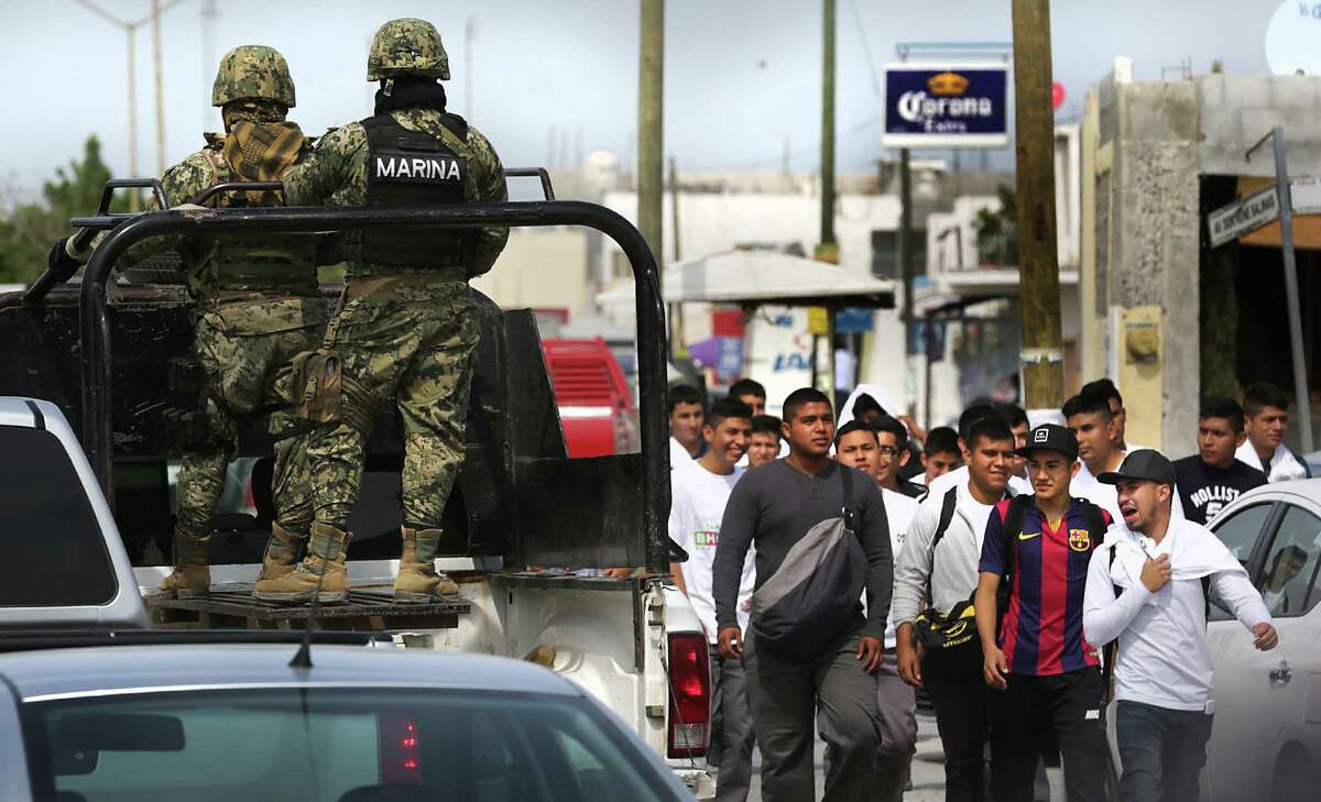 A patrol of Mexican Marines pass by a group of young men on their way to a rally for Tamaulipas gebernatorial PAN candidate Baltazar Hinojosa Ochoa in Reynosa, Wednesday, April 6, 2016. Security in the city that has no police department has become a major political issue.