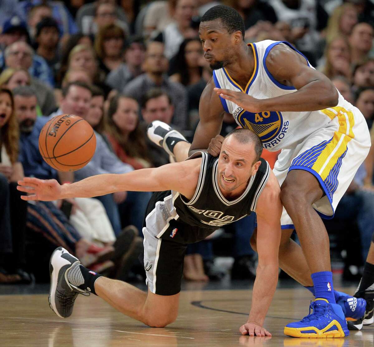 San Antonio Spurs' Manu Ginobili, bottom, of Argentina, chases the ball against Golden State Warriors' Harrison Barnes during the first half of an NBA basketball game, Sunday, April 10, 2016, in San Antonio. (AP Photo/Darren Abate)