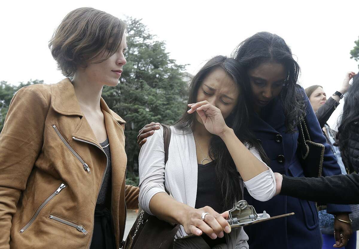 University of California graduate student Kathleen Gutierrez, center, is comforted by graduate student Erin Bennett, left, and Tyann Sorrell before all spoke at a news conference outside of Dwinelle Hall on the campus in Berkeley, Calif., Monday, April 11, 2016. Bennett and Gutierrez have filed a complaint regarding alleged sexual harassment by a University of California Berkeley professor. Sorrell has also made complaints against the same individual for sexual harassment. (AP Photo/Jeff Chiu)