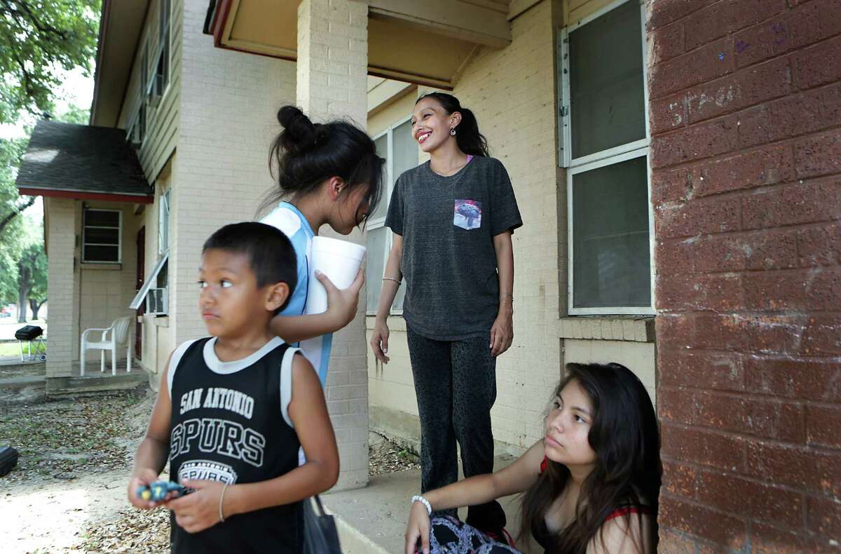 Patricia Martinez smiles at a visitor. With her on the porch of their Cassiano Homes unit are her children, Paul (from left), Rebekah Martinez, and Jerilyn.