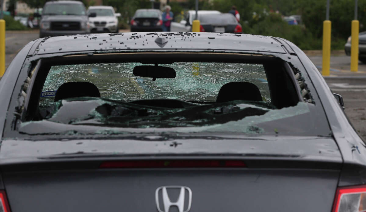 A Honda damaged by hail is in the Wal-Mart parking lot in Helotes after a storm swept through the area last night.