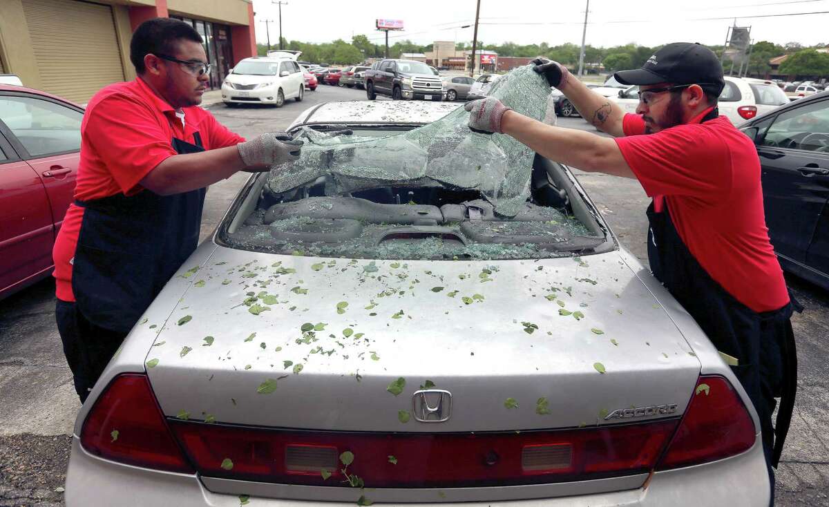 Safelite automotive glass repair company employees Erik White, left, and Jacob Escobar remove broken glass Wednesday, April 13, 2016 at the company's I-10 store location after a widespread overnight hail storm broke windshields throughout large swaths of the city.