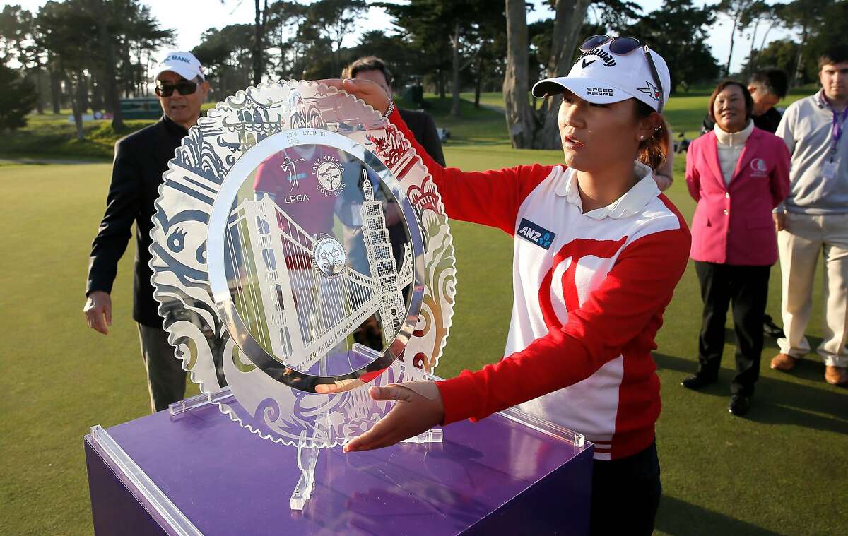 Lydia Ko picks up the champions trophy after her win of the 2015 the Swinging Skirts LPGA Classic golf tournament at Lake Merced Golf Course in Daly City, Calif., on Sun. April 26, 2015.