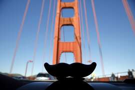 A Lyft mustache on a car dashboard in front of the Golden Gate Bridge near San Francisco, California, on Tuesday, Dec. 29, 2015.