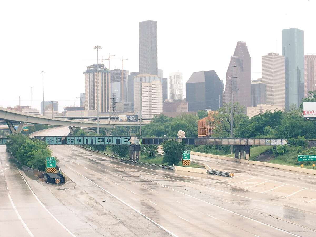 The iconic "Be Someone" graffiti tag sits over an empty, blocked off I-45 heading through downtown. 