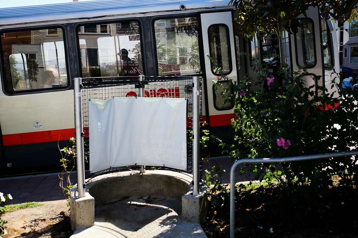A pissoir, an open-air men's toilet, is seen as a Muni train passes behind it, on Church Street in Dolores Park, in San Francisco, California, on Monday, April 18, 2016.