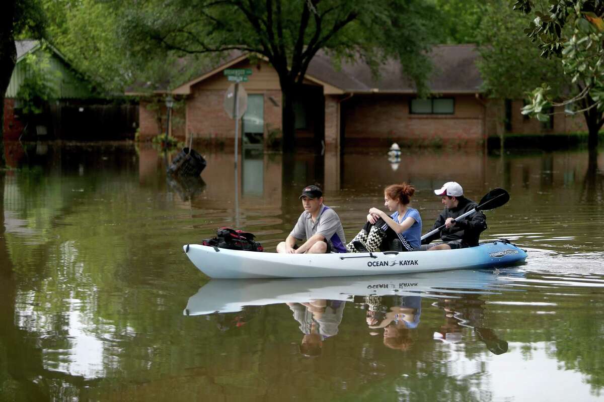 Gideon Miller, Natanya Abramson and Yari Garner canoe along the 9300 block of Greenwillow in the flooded Willow Meadows neighborhood on Monday, April 18. (For more photos of the flood, scroll through the gallery.)