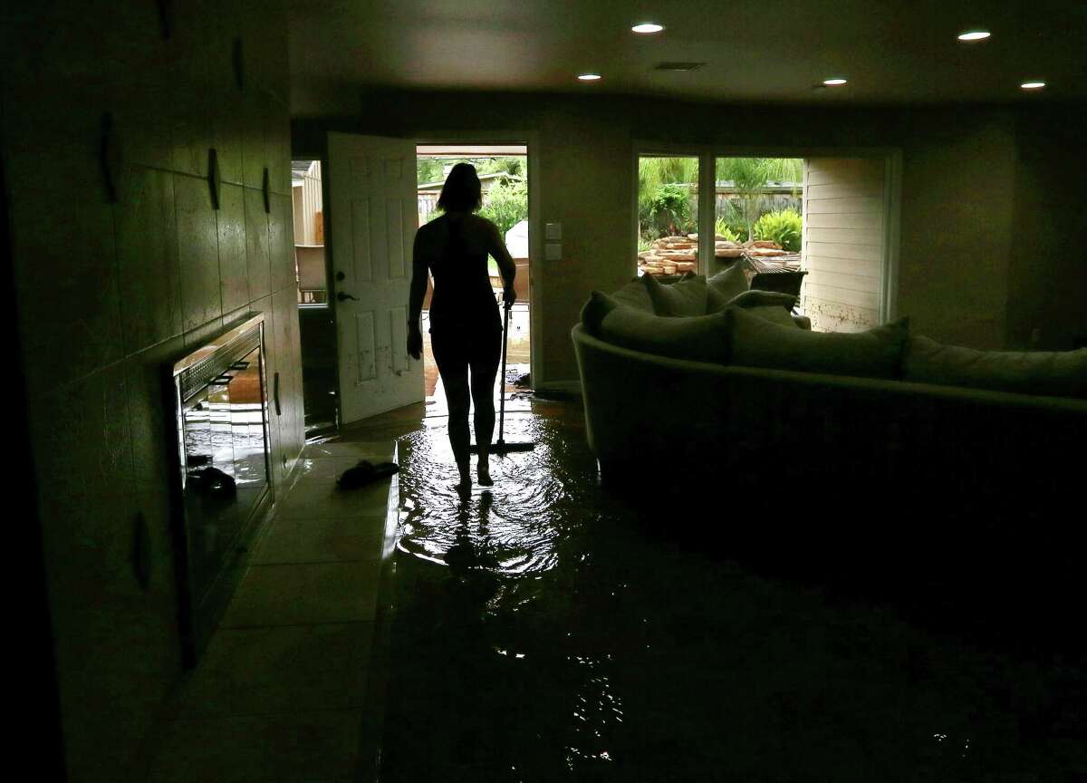 Meital Harari pushes water out the back door at her Meyerland home, Monday, April 18. (For more photos from the Tax Day flood, scroll through the gallery.)