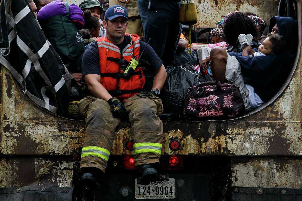 A woman holds her child as firefighters evacuate people from the flooding in the Greenspoint area in dump trucks Monday, April 18, 2016 in Houston.